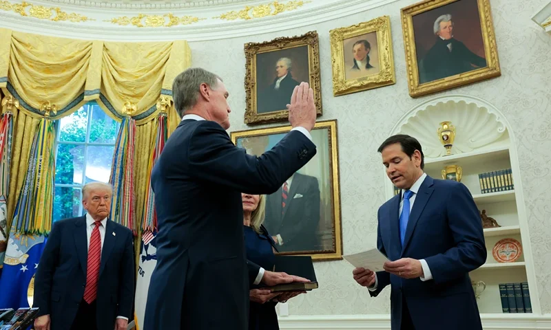 WASHINGTON, DC - MAY 07: U.S. Secretary of State Marco Rubio (R) swears in David Perdue (C) as U.S. Ambassador to China as U.S. President Donald Trump looks on during a ceremony in the Oval Office at the White House on May 07, 2025 in Washington, DC. Perdue, a former Republican Senator and past critic of China and its ruling Communist Party, was confirmed by a vote of 67 to 29 amid a tense trade war between the two countries. (Photo by Anna Moneymaker/Getty Images)