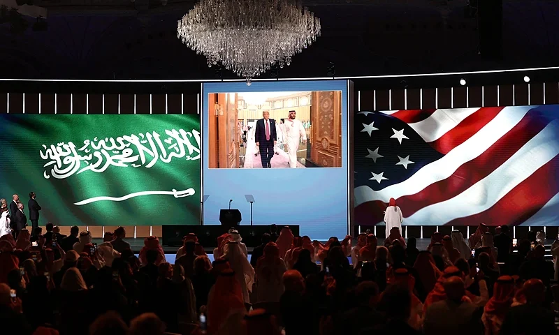 People look to a giant screen as US President Donald Trump and Saudi Crown Prince Mohammed bin Salman arrive for the Saudi-US investment forum at the King Abdul Aziz International Conference Center in Riyadh on May 13, 2025. Saudi Arabia on May 13 promised billions of dollars in deals with the United States from defence to artificial intelligence as it threw a lavish welcome for President Donald Trump on the first state visit of his second term. (Photo by Fayez NURELDINE / AFP) (Photo by FAYEZ NURELDINE/AFP via Getty Images)