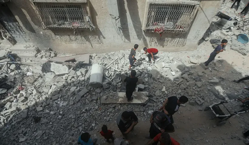 People stand amid rubble and shattered buildings in Gaza City, Palestine, on May 18, 2025. Israeli airstrikes left widespread destruction in residential neighborhoods overnight. (Photo by Youssef Alzanoun / Middle East Images / Middle East Images via AFP) (Photo by YOUSSEF ALZANOUN/Middle East Images/AFP via Getty Images)