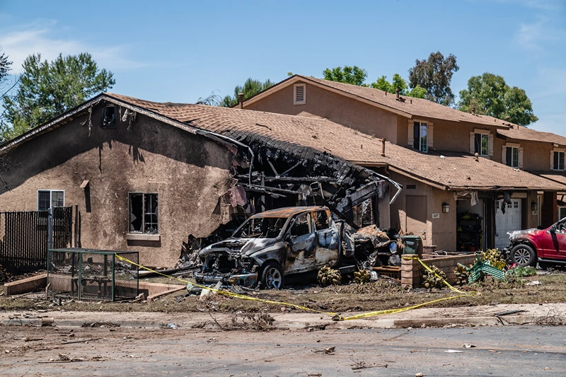 A house is damaged after a small plane crashed into a neighborhood, setting homes and vehicles on fire on May 22, 2025 in San Diego, California. At least two people have died after a Cessna 550 aircraft crashed into a residential street in Murphy Canyon, causing evacuations after buildings were damaged. (Photo by Ariana Drehsler/Getty Images)