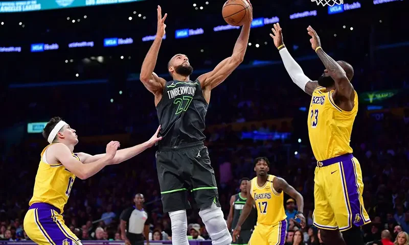 Minnesota Timberwolves center Rudy Gobert (27) gets the rebound against Los Angeles Lakers guard Austin Reaves (15) and forward LeBron James (23) during the second half in game five of first round for the 2025 NBA Playoffs at Crypto.com Arena. Mandatory Credit: Gary A. Vasquez-Imagn Images