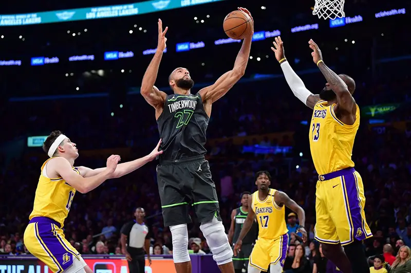 Minnesota Timberwolves center Rudy Gobert (27) gets the rebound against Los Angeles Lakers guard Austin Reaves (15) and forward LeBron James (23) during the second half in game five of first round for the 2025 NBA Playoffs at Crypto.com Arena. Mandatory Credit: Gary A. Vasquez-Imagn Images