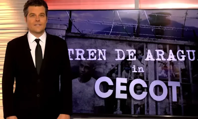 OAN’s Matt Gaetz stands in front of a screen with the text "Tren De Aragua in Cecot" as he promotes the show OAN Investigates.