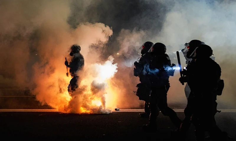 TOPSHOT - Oregon Police wearing anti-riot gear march towards protesters through tear gas smoke during the 100th day and night of protests against racism and police brutality in Portland, Oregon, on September 5, 2020. Police arrested dozens of people and used tear gas against hundreds of demonstrators in Portland late on September 5 as the western US city marked 100 days since Black Lives Matter protests erupted against racism and police brutality. Protests in major US cities erupted after the death of African American George Floyd in May 2020 at the hands of a white police officer in Minneapolis. (Photo by Allison Dinner / AFP) (Photo by ALLISON DINNER/AFP via Getty Images)
