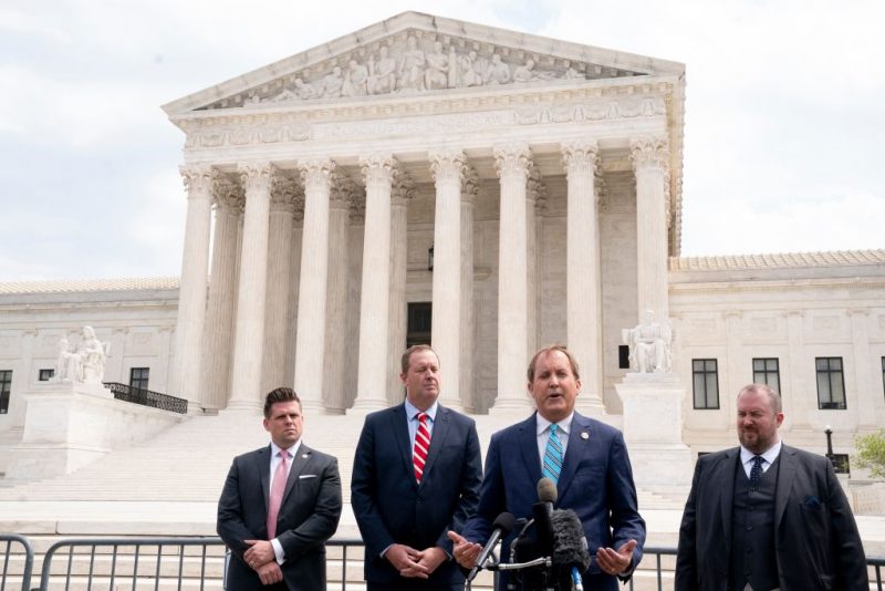 Texas Attorney General Ken Paxton (2R) and Missouri Attorney General Eric Schmitt (2L) speak to reporters in front of the US Supreme Court in Washington, DC, on April 26, 2022. - The Supreme Court will hear oral arguments Tuesday in the Biden v. Texas case, which will determine if the Biden administration must continue to enforce a Trump-era program known as the remain in Mexico policy. The court is considering whether President Joe Biden can end a controversial Trump-era border policy that denies asylum-seekers entry to the US while their case is reviewed. (Photo by Stefani Reynolds / AFP) (Photo by STEFANI REYNOLDS/AFP via Getty Images)