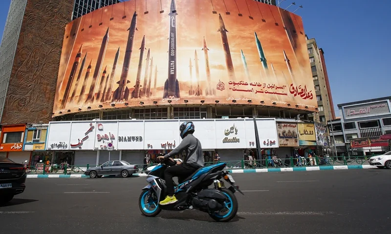 TOPSHOT - A man rides a motorbike past a billboard depicting Iranian ballistic missiles in service in Tehran on April 19, 2024. Iran's state media reported explosions in the central province of Isfahan on April 19, as US media quoted officials saying Israel had carried out retaliatory strikes on its arch-rival. (Photo by AFP) (Photo by -/AFP via Getty Images)