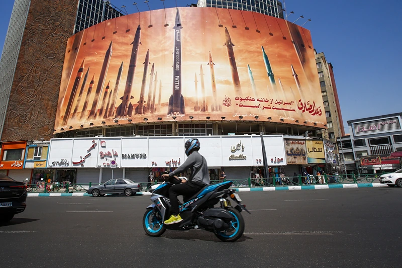 TOPSHOT - A man rides a motorbike past a billboard depicting Iranian ballistic missiles in service in Tehran on April 19, 2024. Iran's state media reported explosions in the central province of Isfahan on April 19, as US media quoted officials saying Israel had carried out retaliatory strikes on its arch-rival. (Photo by AFP) (Photo by -/AFP via Getty Images)