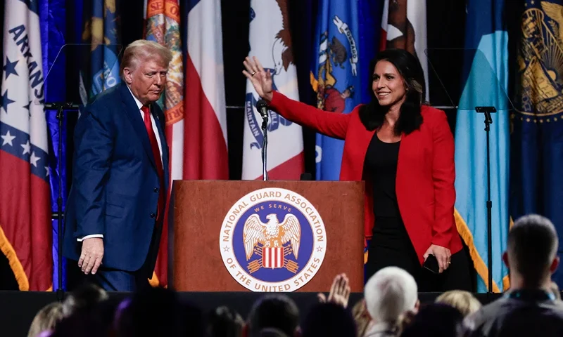 Former US Representative Tulsi Gabbard (R) waves after endorsing former US President and 2024 Republican presidential candidate Donald Trump (L) at the National Guard Association conference in Detroit, Michigan, on August 26, 2024. (Photo by JEFF KOWALSKY / AFP) (Photo by JEFF KOWALSKY/AFP via Getty Images)