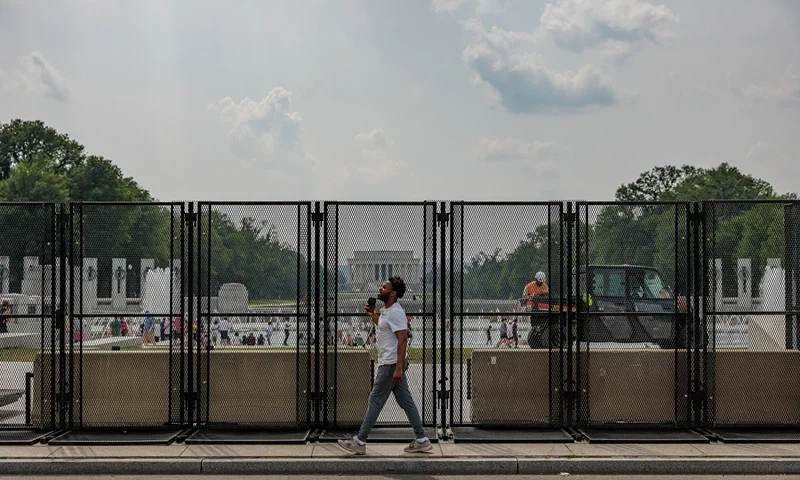 A person walks past anti-scale security fencing on the National Mall in Washington, D.C. on June 13, 2025 ahead of a parade and festival celebrating the 250th anniversary of the U.S. Army. (Photo by Bryan Dozier / Middle East Images via AFP) (Photo by BRYAN DOZIER/Middle East Images/AFP via Getty Images)