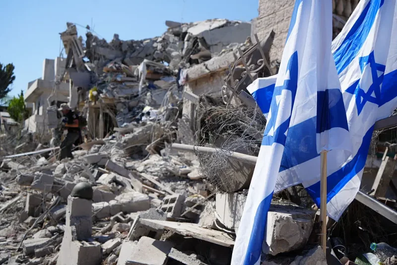 Israeli flags stand amid rubble and destruction in a residential area of Rishon LeZion, Israel on June 14, 2025. Extensive damage happened as a result of Iran's retaliatory strike involving around 100 missiles, launched after Israel attacked Iran on the night of June 1213, 2025. (Photo by Khadija Toufik / Middle East Images via AFP) (Photo by KHADIJA TOUFIK/Middle East Images/AFP via Getty Images)