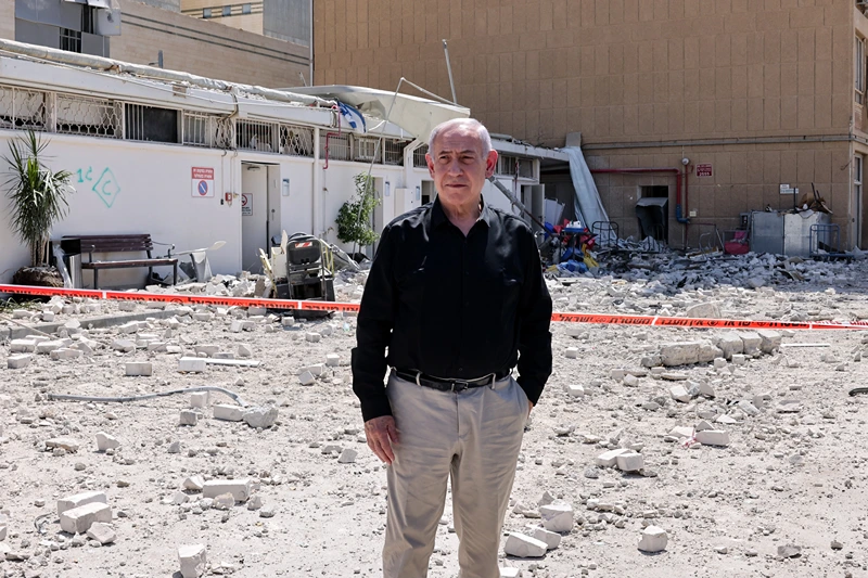 Israeli Prime Minister Benjamin Netanyahu stands amid debris outside the Soroka Hospital in the southern city of Beersheba, after it was hit by a missile fired from Iran on June 19, 2025. Israel's defence minister warned that Iran's supreme leader "can no longer be allowed to exist" after a hospital was hit in an Iranian missile strike on June 19, spiking tensions in the week-old war. (Photo by Marc Israel SELLEM / POOL / AFP) (Photo by MARC ISRAEL SELLEM/POOL/AFP via Getty Images)