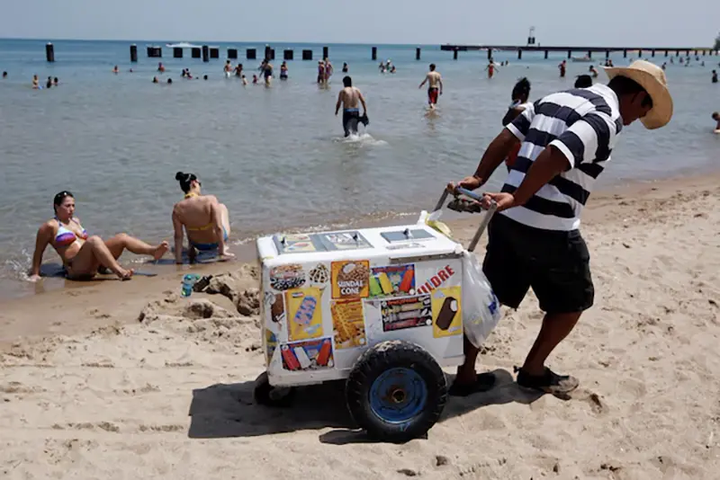 A vendor drags his ice cream cooler across North Avenue Beach in Chicago July 20, 2011. REUTERS/Jim Young/File Photo