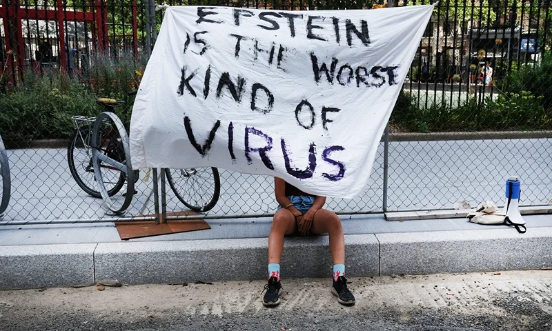 NEW YORK, NEW YORK - JULY 14: A woman protesting against Jeffrey Epstein takes in the shade while outside a Manhattan courthouse where media has gathered for the arraignment hearing of Ghislaine Maxwell on July 14, 2020 in New York City. Maxwell, the British socialite, longtime girlfriend and alleged accomplice of deceased, accused sex-trafficker Jeffrey Epstein, was recently arrested in New Hampshire and is charged by New York federal prosecutors with six counts in connection with the ongoing federal investigation into Epstein's accomplices. Calling her a flight risk, prosecutors want Maxwell, 58 and who will appear at the hearing via a video link, remanded. (Photo by Spencer Platt/Getty Images)