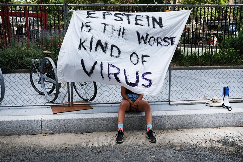 NEW YORK, NEW YORK - JULY 14: A woman protesting against Jeffrey Epstein takes in the shade while outside a Manhattan courthouse where media has gathered for the arraignment hearing of Ghislaine Maxwell on July 14, 2020 in New York City. Maxwell, the British socialite, longtime girlfriend and alleged accomplice of deceased, accused sex-trafficker Jeffrey Epstein, was recently arrested in New Hampshire and is charged by New York federal prosecutors with six counts in connection with the ongoing federal investigation into Epstein's accomplices. Calling her a flight risk, prosecutors want Maxwell, 58 and who will appear at the hearing via a video link, remanded. (Photo by Spencer Platt/Getty Images)
