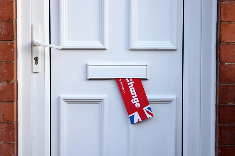 A Labour Party leaflet hangs from a letter box near a polling station in Loughborough, central England, on July 4, 2024 as Britain holds a general election. Voters will cast ballots from 7:00 am (0600 GMT), with polls predicting that Labour will win its first general election since 2005 -- making its leader Keir Starmer prime minister. (Photo by Darren Staples / AFP) (Photo by DARREN STAPLES/AFP via Getty Images