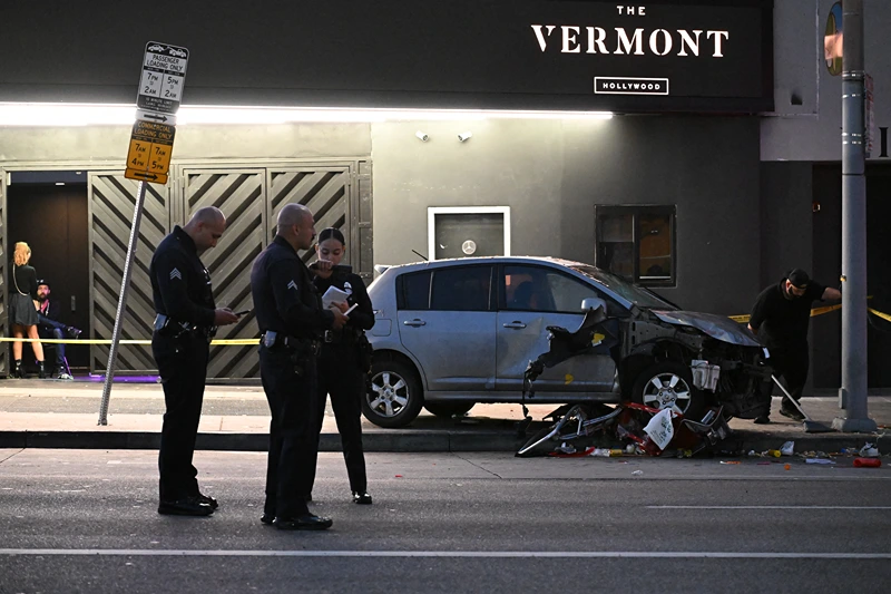 Officers stand at the scene of a crashed vehicle which drove into a crowd in Hollywood in the early hours of July 19, 2025, injuring 28 people, according to the Los Angeles Fire Department. More than 100 firefighters responded to the scene in East Hollywood assisting three patients in critical condition, six in serious condition and 19 listed as fair, the Fire Department said. (Photo by Robyn Beck / AFP) (Photo by ROBYN BECK/AFP via Getty Images)