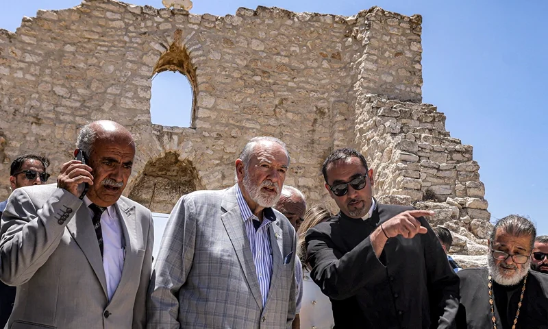 TOPSHOT - US ambassador to Israel Mike Huckabee (C) and the Palestinian mayor of the village of Taybeh, Suleiman Khourieh (L), tour the fifth-century Church of St George in the Palestinian Christian village of Taybeh, northeast of Ramallah in the occupied West Bank, on July 19, 2025. In the villages and communities around Taybeh, Palestinian authorities have reported that settlers had killed three people and damaged or destroyed multiple water sources in the past two weeks alone. The July 7 arson attack on the remains of the Church of Saint George, which date back to the 5th century, was the last straw for many villagers, who blame Israeli settlers for a spate of recent attacks. (Photo by JAAFAR ASHTIYEH / AFP) (Photo by JAAFAR ASHTIYEH/AFP via Getty Images)