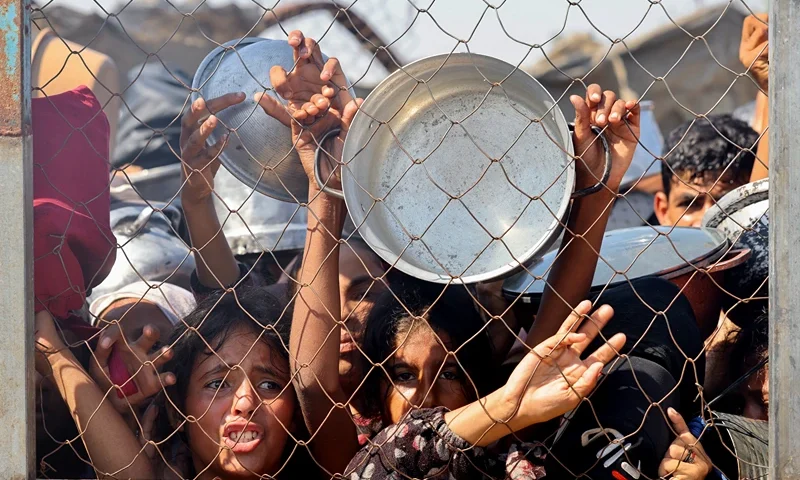 TOPSHOT - Palestinians, mostly children, push to receive a hot meal at a charity kitchen in the Mawasi area of Khan Yunis in the southern Gaza Strip on July 22, 2025. The head of Gaza's largest hospital said 21 children have died due to malnutrition and starvation in the Palestinian territory in the past three days, amid a devastating assault by Israeli forces. (Photo by AFP) (Photo by -/AFP via Getty Images)