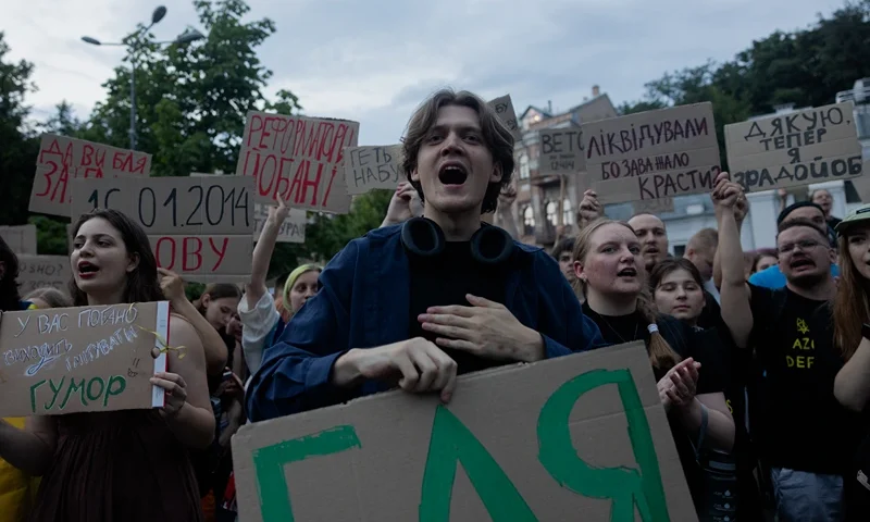 TOPSHOT - Protesters hold placards during a demonstration calling for the Ukrainian president to veto a law passed by parliament that reduces the powers of Ukraine's National Anti-Corruption Bureau (NABU) and Specialised Anti-Corruption Prosecutor's Office (SAPO) in downtown Kyiv on July 22, 2025, amid the Russian invasion of Ukraine. Ukraine's parliament voted on July 22 to revoke the autonomy of the two anti-corruption agencies, a move that critics say will allow government meddling in high-profile graft cases. (Photo by Tetiana DZHAFAROVA / AFP) (Photo by TETIANA DZHAFAROVA/AFP via Getty Images)