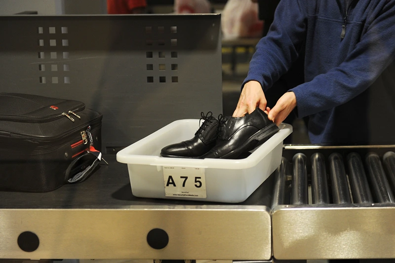 An air traveler places his shoes in a bin before passing through the Transportation Security Administration (TSA) security check at Los Angeles International Airport (LAX) on February 20, 2014 in Los Angeles, California. The TSA recently launched a PreCheck program that allows those enrolled in a trusted traveler network to enter about 100 US airports through a special security lane where they dont have to take off shoes, belts and jackets or remove laptops, liquids or gels. AFP PHOTO / ROBYN BECK (Photo credit should read ROBYN BECK/AFP via Getty Images)
