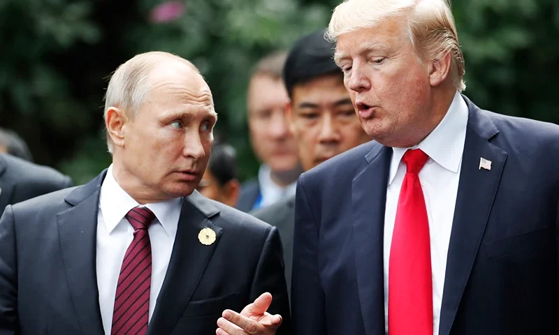 US President Donald Trump (R) and Russia's President Vladimir Putin talk as they make their way to take the "family photo" during the Asia-Pacific Economic Cooperation (APEC) leaders' summit in the central Vietnamese city of Danang on November 11, 2017. World leaders and senior business figures are gathering in the Vietnamese city of Danang this week for the annual 21-member APEC summit. (Photo by JORGE SILVA / POOL / AFP) (Photo by JORGE SILVA/POOL/AFP via Getty Images)