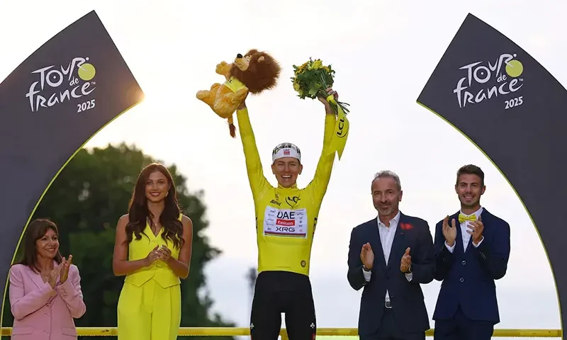 UAE Team Emirates XRG's Tadej Pogacar celebrates on the podium wearing the yellow jersey after winning the Tour de France, as Paris' mayor Anne Hidalgo applauds REUTERS/Sarah Meyssonnier