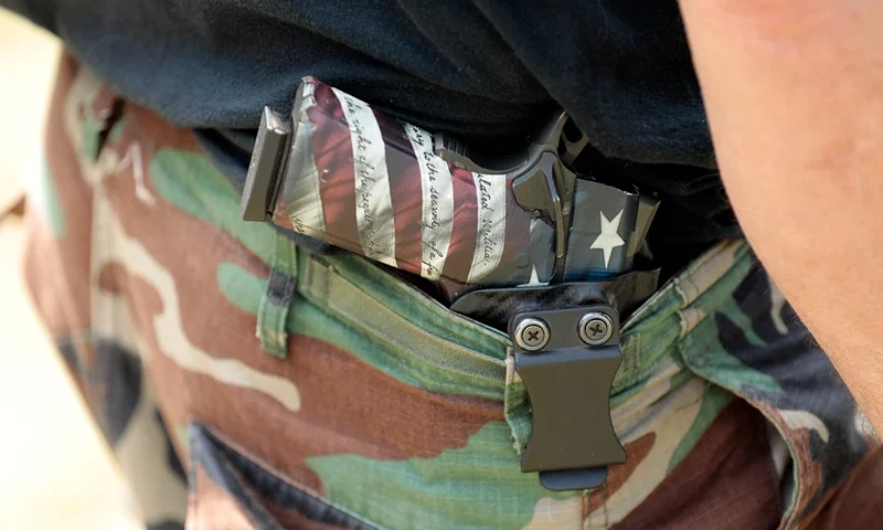 People carry weapons during the Defend Our Second Amendment: Michigan's fight for Self Preservation rally, held in a farm field in Ionia, Michigan, on July 19 2023. In 2021, the Capitol Commission in Michigan banned the open carry of weapons within the Capitol building, and is expected to vote on a full ban by its August meeting. Members of the group Sons of Liberty PAC created the Defend Our 2A: Michigan's fight for Self Preservation rally to protest the ban, saying that people's rights in Michigan are being eroded. (Photo by JEFF KOWALSKY / AFP) (Photo by JEFF KOWALSKY/AFP via Getty Images)