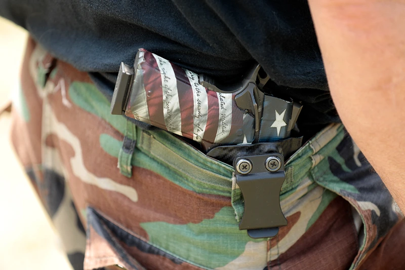 People carry weapons during the Defend Our Second Amendment: Michigan's fight for Self Preservation rally, held in a farm field in Ionia, Michigan, on July 19 2023. In 2021, the Capitol Commission in Michigan banned the open carry of weapons within the Capitol building, and is expected to vote on a full ban by its August meeting. Members of the group Sons of Liberty PAC created the Defend Our 2A: Michigan's fight for Self Preservation rally to protest the ban, saying that people's rights in Michigan are being eroded. (Photo by JEFF KOWALSKY / AFP) (Photo by JEFF KOWALSKY/AFP via Getty Images)