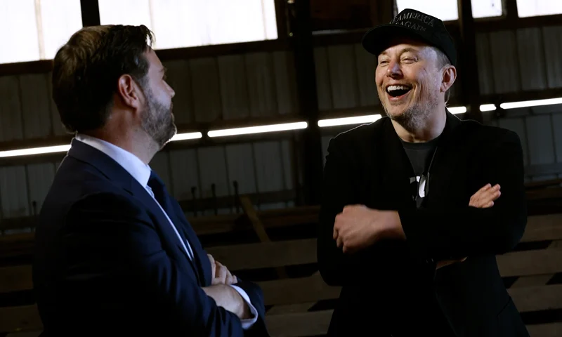 BUTLER, PENNSYLVANIA - OCTOBER 05: Elon Musk (R) dons a black "Make America Great Again" ball cap while talking with Republican vice presidential Nominee Sen. JD Vance back stage during a campaign rally at the Butler Farm Show grounds on October 05, 2024 in Butler, Pennsylvania. This is the first time that Republican presidential nominee, former President Donald Trump has returned to Butler since he was injured during an attempted assassination on July 13. (Photo by Anna Moneymaker/Getty Images)