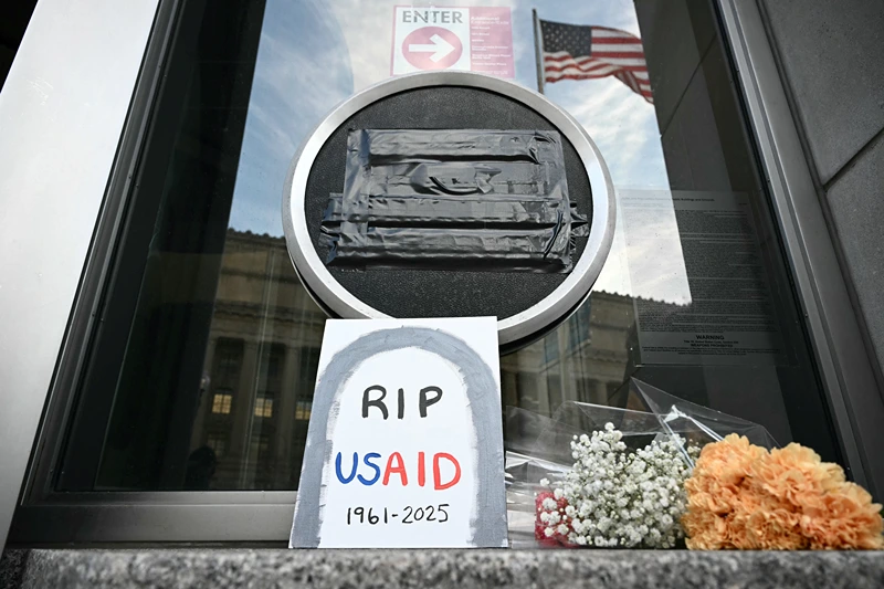 TOPSHOT - Tributes are placed beneath the covered seal of the US Agency for International Development (USAID) at their headquarters in Washington, DC, on February 7, 2025. US President Donald Trump on February 7, 2025 called for USAID to be shuttered, escalating his unprecedented campaign to dismantle the humanitarian agency. (Photo by Mandel NGAN / AFP) (Photo by MANDEL NGAN/AFP via Getty Images)