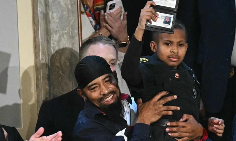 13-year-old cancer survivor Devarjaye "DJ" Daniel is lifted up by his father Theodis Daniel after given credentials from US Secret Service Director Sean Curran after US President Donald Trump made him an honorary member of the US Secret Service during his address to a joint session of Congress at the US Capitol in Washington, DC, on March 4, 2025. (Photo by SAUL LOEB / AFP) (Photo by SAUL LOEB/AFP via Getty Images)