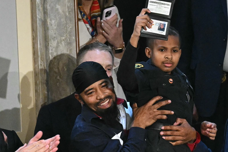 13-year-old cancer survivor Devarjaye "DJ" Daniel is lifted up by his father Theodis Daniel after given credentials from US Secret Service Director Sean Curran after US President Donald Trump made him an honorary member of the US Secret Service during his address to a joint session of Congress at the US Capitol in Washington, DC, on March 4, 2025. (Photo by SAUL LOEB / AFP) (Photo by SAUL LOEB/AFP via Getty Images)