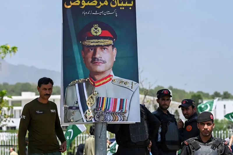 Security personnel stand beside a poster of Pakistani Army Chief General Syed Asim Munir, during a rally to express solidarity with Pakistan's armed forces, in Islamabad on May 14, 2025. The brief conflict between India and Pakistan last week may have left no clear victor, but Islamabad's generals are taking a win, riding a wave of approval on social media to burnish their recently tarnished image. (Photo by Aamir QURESHI / AFP) (Photo by AAMIR QURESHI/AFP via Getty Images)