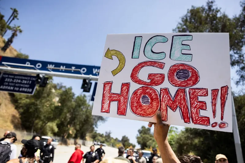 A demonstrator holds a poster reading "ICE go home" in front of one of the parking lot entrances at Dodgers Stadium, where federal immigration agents were denied entry, in Los Angeles, California on June 19, 2025. Federal immigration agents were barred from entering Dodger Stadium on June 19 after requesting access to the Major League Baseball team's grounds, the team confirmed. US Immigration and Customs Enforcement (ICE) agents arrived at the stadium and "requested permission to access the parking lots," the Dodgers said in a statement. (Photo by ETIENNE LAURENT / AFP) (Photo by ETIENNE LAURENT/AFP via Getty Images)