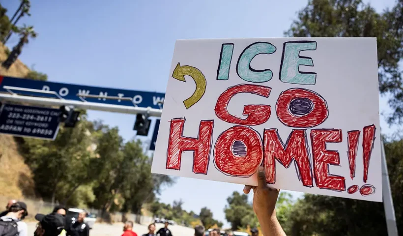 A demonstrator holds a poster reading "ICE go home" in front of one of the parking lot entrances at Dodgers Stadium, where federal immigration agents were denied entry, in Los Angeles, California on June 19, 2025. Federal immigration agents were barred from entering Dodger Stadium on June 19 after requesting access to the Major League Baseball team's grounds, the team confirmed. US Immigration and Customs Enforcement (ICE) agents arrived at the stadium and "requested permission to access the parking lots," the Dodgers said in a statement. (Photo by ETIENNE LAURENT / AFP) (Photo by ETIENNE LAURENT/AFP via Getty Images)