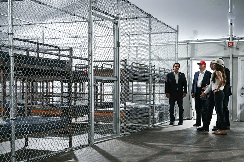 TOPSHOT - US President President Donald Trump (2L), Florida Governor Ron DeSantis (L), and Secretary of Homeland Security Kristi Noem (R) tour a migrant detention center, dubbed "Alligator Alcatraz," located at the site of the Dade-Collier Training and Transition Airport in Ochopee, Florida on July 1, 2025. President Trump is visiting a migrant detention center in a reptile-infested Florida swamp dubbed "Alligator Alcatraz." Trump will attend the opening of the 5,000-bed facility -- located at an abandoned airfield in the Everglades wetlands -- part of his expansion of deportations of undocumented migrants, his spokeswoman said. (Photo by ANDREW CABALLERO-REYNOLDS / AFP) (Photo by ANDREW CABALLERO-REYNOLDS/AFP via Getty Images)