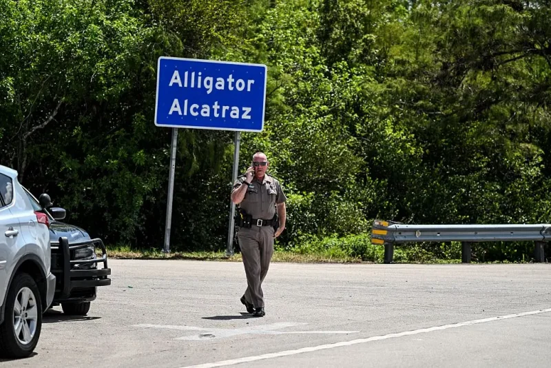 A Florida Highway Patrol officer looks on as protesters gather to demand the closure of the immigrant detention center known as "Alligator Alcatraz" at the Dade-Collier Training and Transition Airport in Ochopee, Florida, on July 22, 2025. Immigrants held at US detention centers have experienced abusive and degrading treatment, a Human Rights Watch report said on July 21. (Photo by CHANDAN KHANNA / AFP) (Photo by CHANDAN KHANNA/AFP via Getty Images)