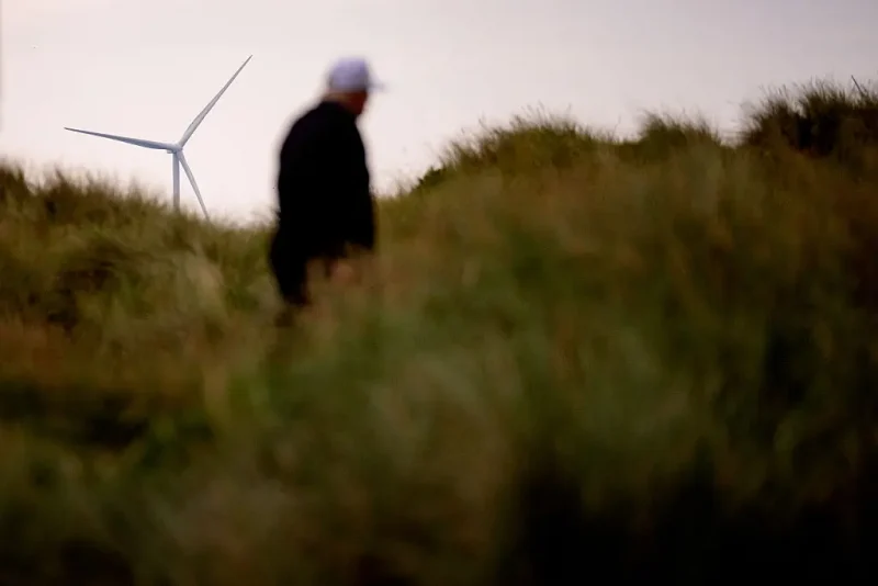 BALMEDIE, SCOTLAND - JULY 29: A windmill turbine is visible as U.S. President Donald Trump walks after teeing off at a new 18-hole course at Trump International Golf Links on July 29, 2025 in Balmedie, near Aberdeen, Scotland. President Trump is visiting Scotland in a trip that's part-vacation, part-work, as he stayed at his Trump Turnberry golf course, followed by Trump International Golf Links in Aberdeenshire, between July 25 to 29. (Photo by Andrew Harnik/Getty Images)
