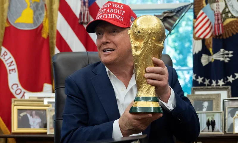 US President Donald Trump holds the World Cup trophy in the Oval Office of the White House in Washington, DC, on August 22, 2025. Trump announced the 2026 World Cup draw will be held on December 5 at Washington's Kennedy Center. (Photo by ANDREW CABALLERO-REYNOLDS / AFP) (Photo by ANDREW CABALLERO-REYNOLDS/AFP via Getty Images)