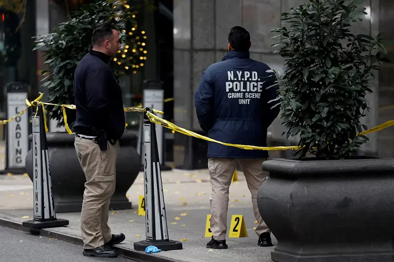 Law enforcement officers work near evidence markers placed where shell casings were found at the scene where the CEO of UnitedHealthcare Brian Thompson was shot and killed in Midtown Manhattan, in New York City, US, December 4, 2024.REUTERS/Shannon Stapleton/File Photo