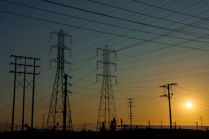 Electrical transmission towers and lines are shown in the early morning of a hot summer day in Commerce, California, U.S, August 7, 2025. REUTERS/Mike Blake/File Photo
