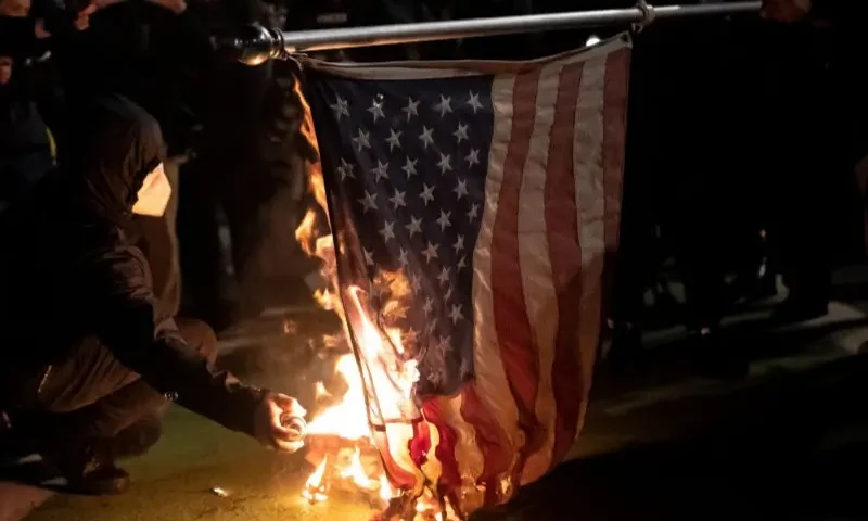 Black bloc protesters burn an American flag on November 4, 2020 in Portland, Oregon. Multiple protests, some peaceful and others violent, broke out in Portland as the presidential election remained undecided. (Photo by Nathan Howard/Getty Images)