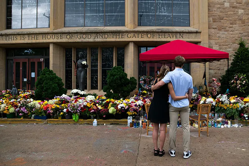 People embrace outside of Annunciation Church and School on September 2, 2025 in Minneapolis, Minnesota. (Photo by Stephen Maturen/Getty Images)