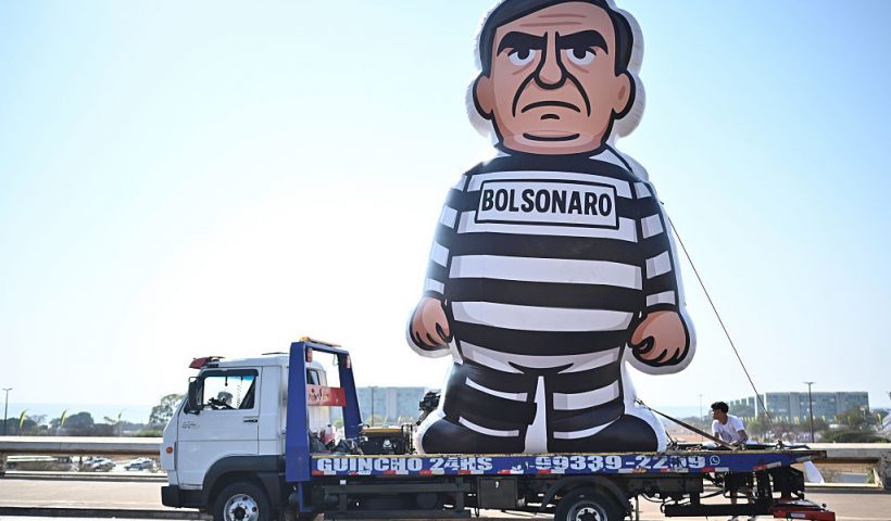 BRASILIA, BRAZIL - SEPTEMBER 12: A truck carries an inflatable doll representing former President of Brazil Jair Bolsonaro in prison uniform the day after Supreme Court of Brazil confirmed his prison sentence on September 12, 2025 in Brasilia, Brazil. Bolsonaro ruled the country between 2019 and 2022 and has been sentenced to 27 years in prison over a coup plot after being defeated by Lula Da Silva in the 2022 presidential election. The right-wing former president also faces four more charges against the democratic order. (Photo by Ton Molina/Getty Images)