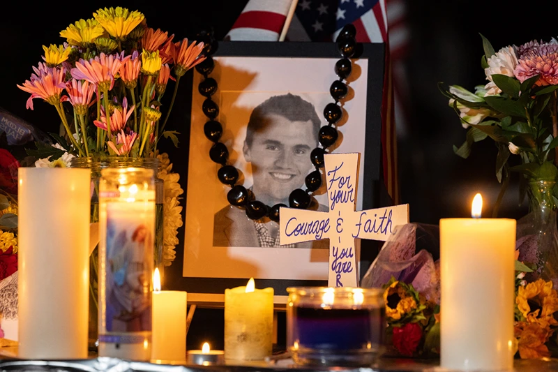 Candles and flowers are seen near a portrait of right-wing activist Charlie Kirk at a makeshift memorial during a candlelight vigil at Memorial Park in Provo, Utah, on September 12, 2025, after he was shot during a public event at Utah Valley University. The widow of prominent right-wing activist Charlie Kirk pledged on September 12 to carry on her husband's work, after US authorities announced his alleged assassin had finally been captured. The 31-year-old Kirk was hit by a single bullet while addressing a large crowd at Utah Valley University in the town of Orem on September 10. (Photo by Melissa MAJCHRZAK / AFP) (Photo by MELISSA MAJCHRZAK/AFP via Getty Images)