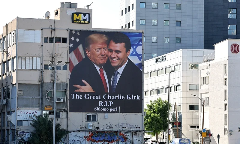 A billboard showing an image of US President Donald Trump (L) embracing US prominent right-wing activist Charlie Kirk, who was hit by a single bullet while addressing a large crowd at Utah Valley University in the town of Orem on September 10, hangs on the side of a building in Tel Aviv, on September 13, 2025. Trump on September 12, announced that the suspect had been taken into custody over the killing of right-wing activist Charlie Kirk after a massive manhunt. (Photo by Jack GUEZ / AFP) (Photo by JACK GUEZ/AFP via Getty Images)