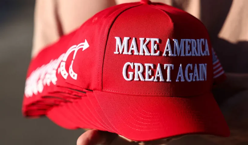A member of Turning Point USA distributes MAGA hats to people gathered at a makeshift memorial for right-wing activist and Turning Point USA founder Charlie Kirk outside of their headquarters in Phoenix, Arizona, on September 19, 2025. The widow of slain right-wing activist Charlie Kirk is to take his place at the head of youth action campaign group Turning Point USA, officials announced on September 18. Two days after her husband was shot dead on a univerity campus, allegedly by a 22-year-old gunman, Erika Kirk told supporters: "The movement my husband built will not die." (Photo by CHARLY TRIBALLEAU / AFP) (Photo by CHARLY TRIBALLEAU/AFP via Getty Images)