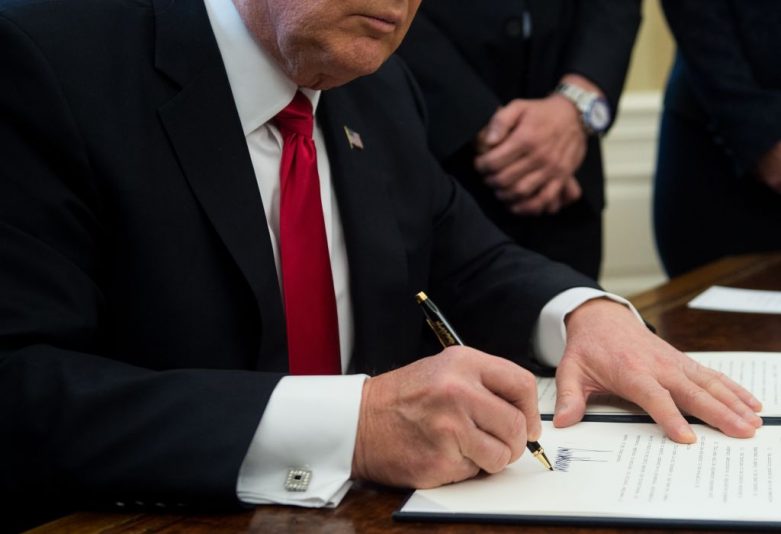 US President Donald Trump signs an executive order with small business leaders in the Oval Office at the White House in Washington, DC on January 30, 2017. / AFP PHOTO / NICHOLAS KAMM (Photo credit should read NICHOLAS KAMM/AFP via Getty Images)