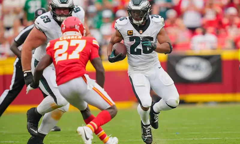 Philadelphia Eagles running back Saquon Barkley (26) carries the ball defended by Kansas City Chiefs safety Chamarri Conner (27) during the fourth quarter of the game at GEHA Field at Arrowhead Stadium. Mandatory Credit: Jay Biggerstaff-Imagn Images