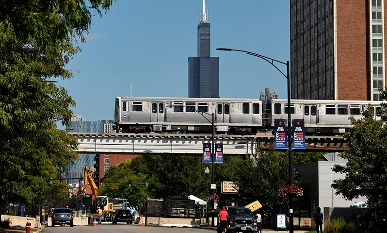 CHICAGO, ILLINOIS - AUGUST 17: A Chicago Transit Authority Pink Line elevated train rolls over the 10-foot-tall security perimeter fence around the the United Center ahead of the next week's Democratic National Convention on August 17, 2024 in Chicago, Illinois. The convention will be held in Chicago on August 19-22. (Photo by Chip Somodevilla/Getty Images)